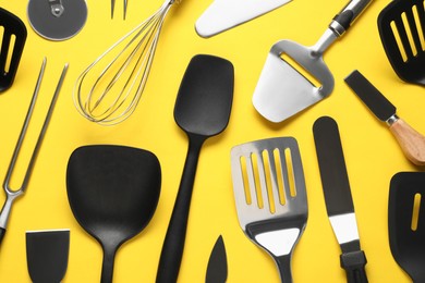 Photo of Different spatulas and other kitchen utensils on yellow background, flat lay