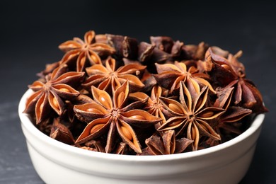 Bowl with aromatic anise stars on dark table, closeup