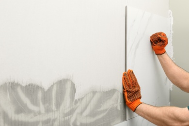 Man installing ceramic tile on wall, space for text. Building and renovation works