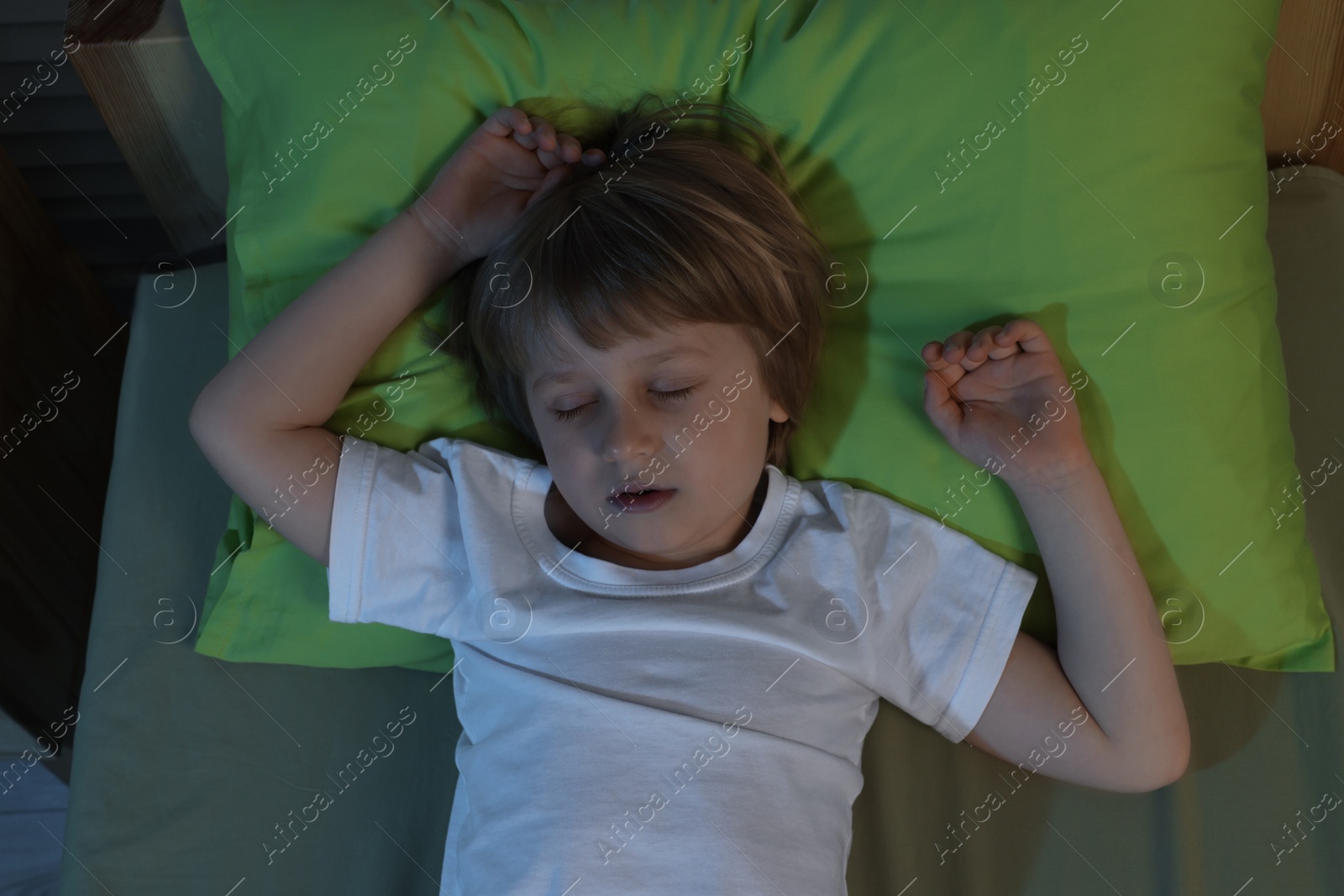 Photo of Little boy snoring while sleeping in bed at night, top view