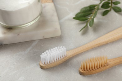 Bamboo toothbrushes and jar of baking soda on light grey marble table, closeup