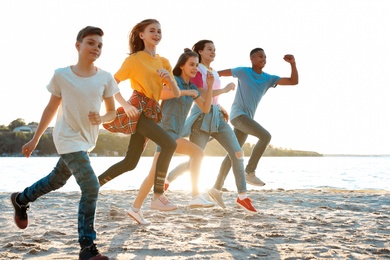 Photo of Group of children running on beach. Summer camp