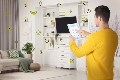 Man using smart home control system via application on tablet indoors. Different icons around him