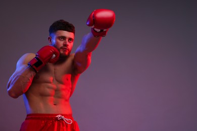 Photo of Man in boxing gloves fighting on color background, low angle view. Space for text