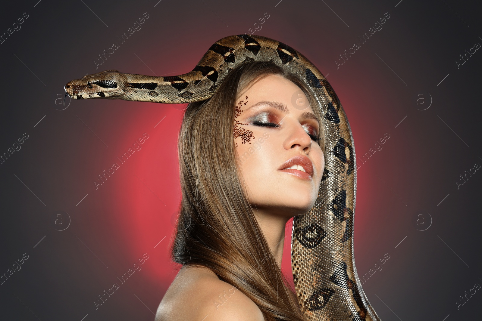 Photo of Beautiful woman with boa constrictor on color background