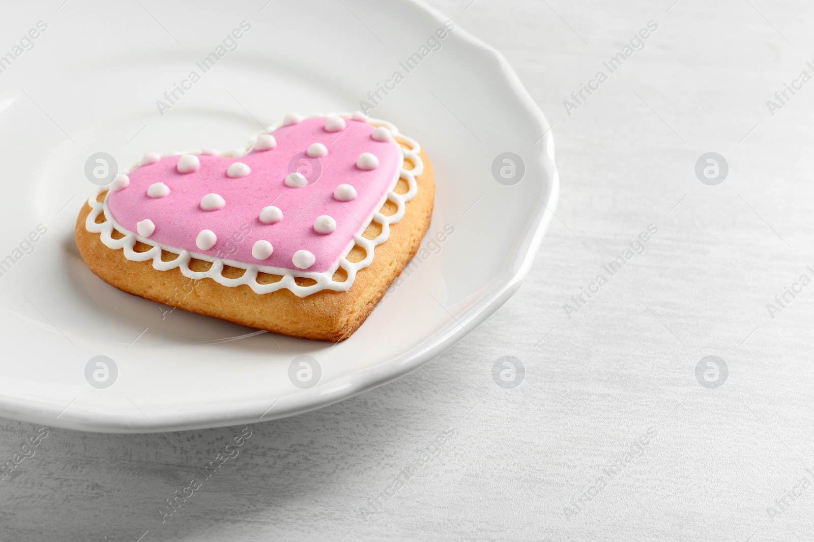 Photo of Plate with decorated heart shaped cookie on wooden table. Space for text