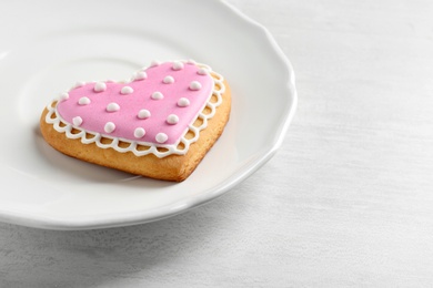 Plate with decorated heart shaped cookie on wooden table. Space for text