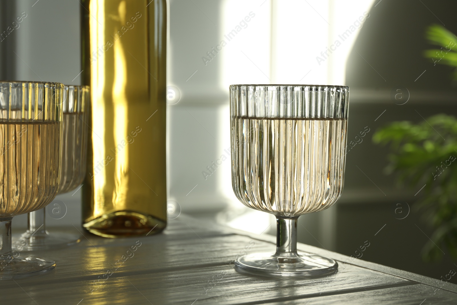 Photo of Alcohol drink in glasses and bottle on wooden table indoors, closeup