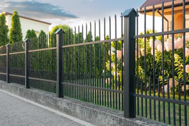 Photo of Beautiful black iron fence near pathway outdoors