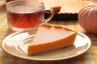 Photo of Piece of fresh homemade pumpkin pie served with tea on table