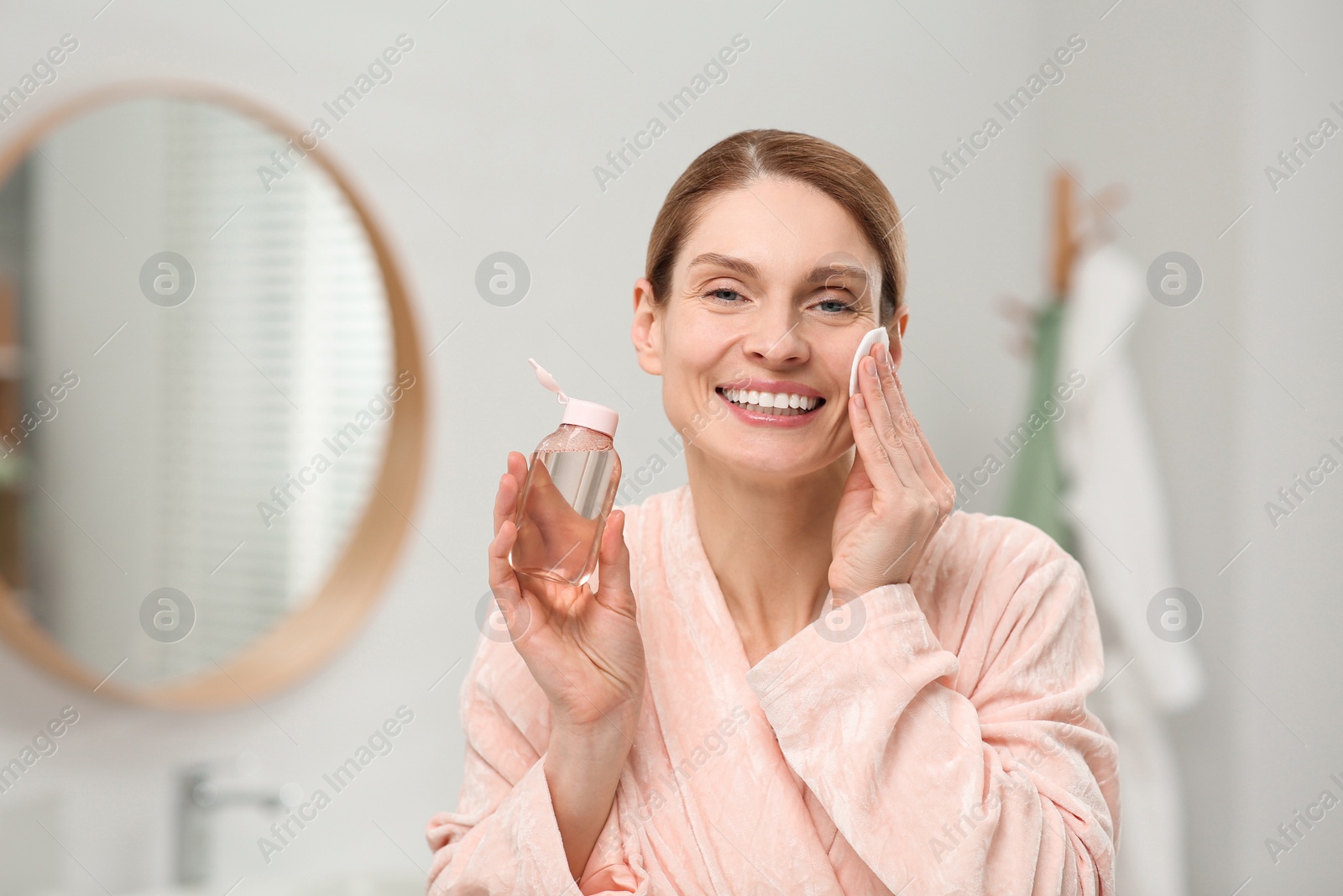 Photo of Beautiful woman removing makeup with cotton pad indoors, space for text