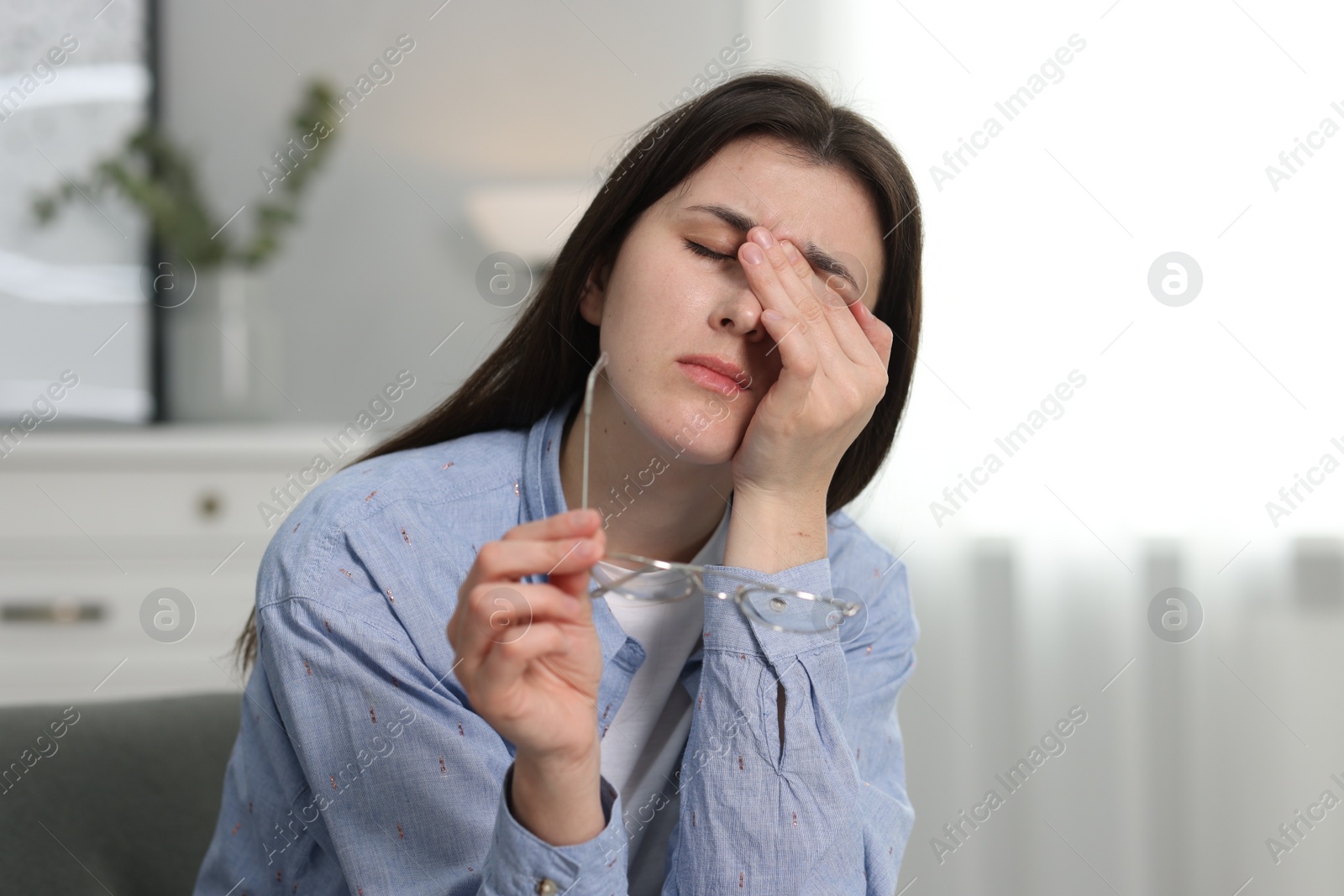 Photo of Overwhelmed woman with glasses suffering from headache at home