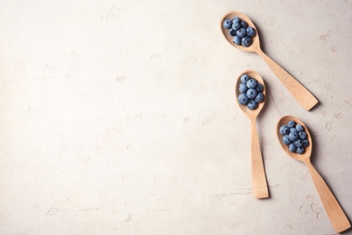Photo of Flat lay composition with spoons and juicy blueberries on color table. Space for text