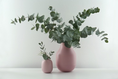 Photo of Beautiful eucalyptus branches and flowers on white table. Interior element