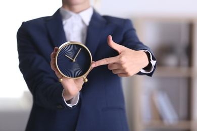 Photo of Businesswoman holding alarm clock on blurred background. Time concept