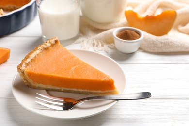 Plate with piece of fresh delicious homemade pumpkin pie on wooden table