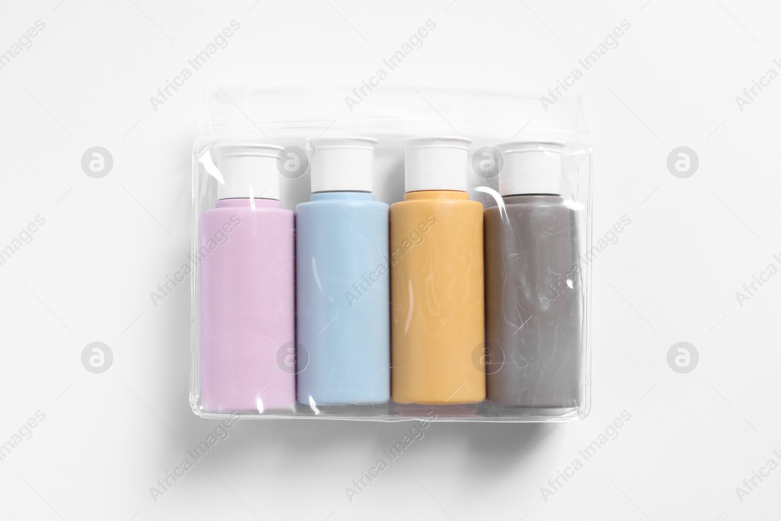 Photo of Cosmetic travel kit in plastic bag on white background, top view