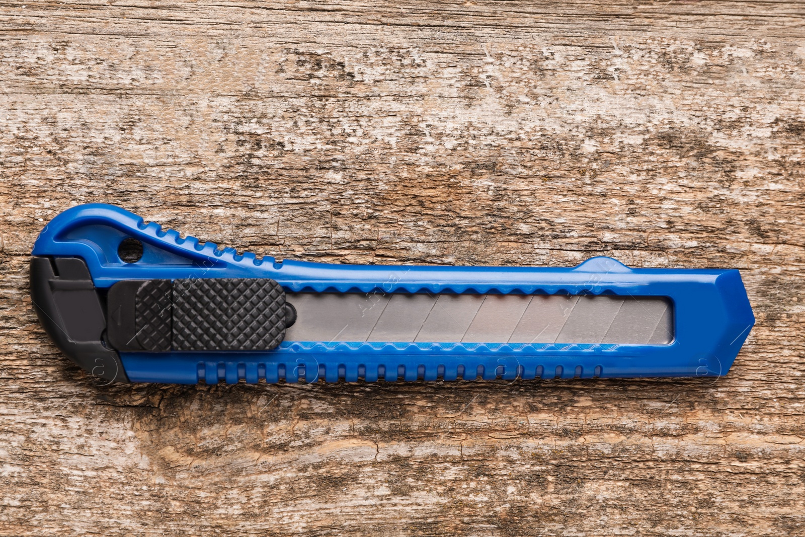 Photo of Blue utility knife on wooden table, top view. Construction tool