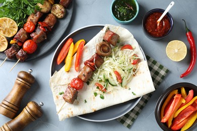 Photo of Delicious shish kebabs with vegetables served on gray table, flat lay