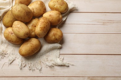 Photo of Raw fresh potatoes on light wooden table, top view. Space for text