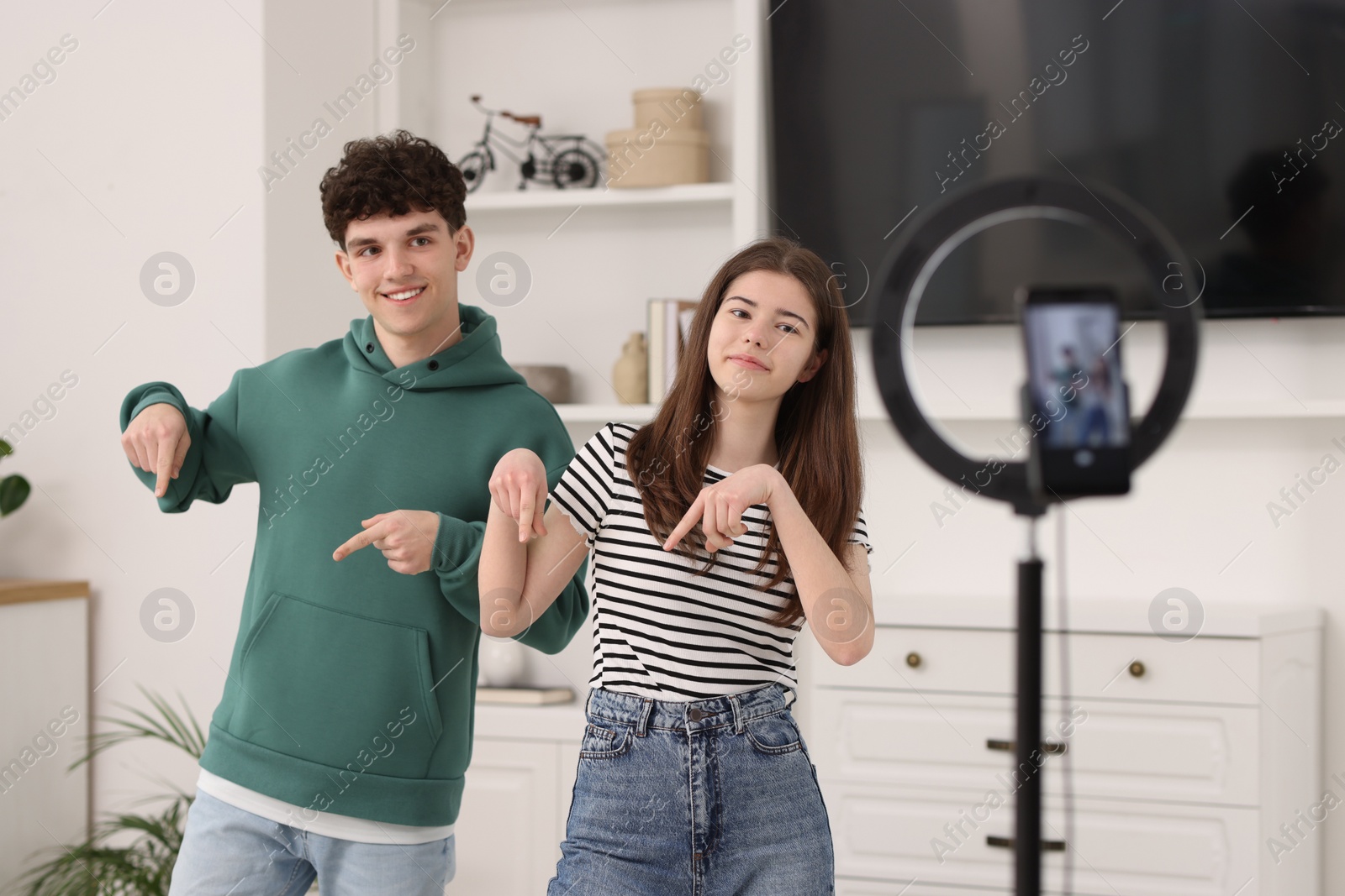 Photo of Smiling teenage bloggers dancing while streaming at home