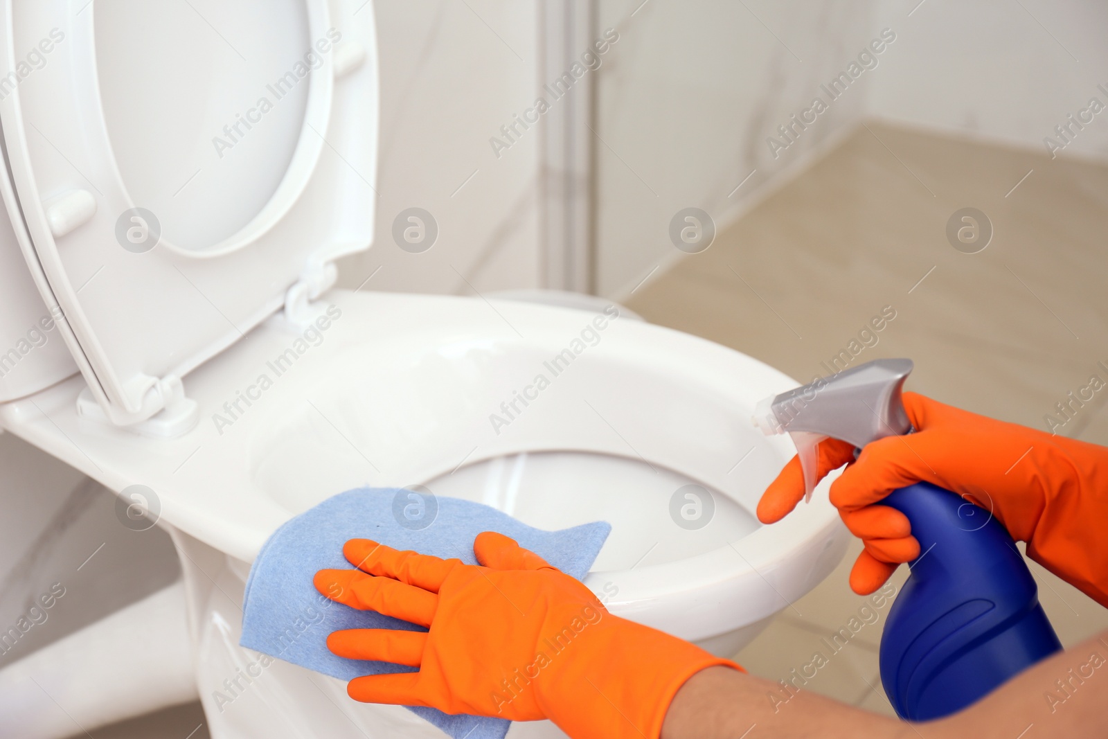 Photo of Woman cleaning toilet bowl in bathroom, closeup