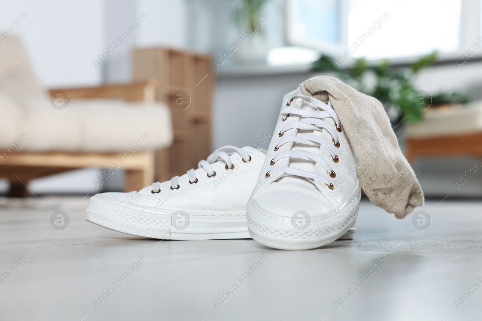 Photo of Sneakers with dirty socks on white wooden floor indoors