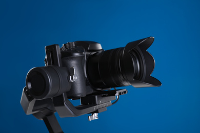 Modern professional video camera on blue background