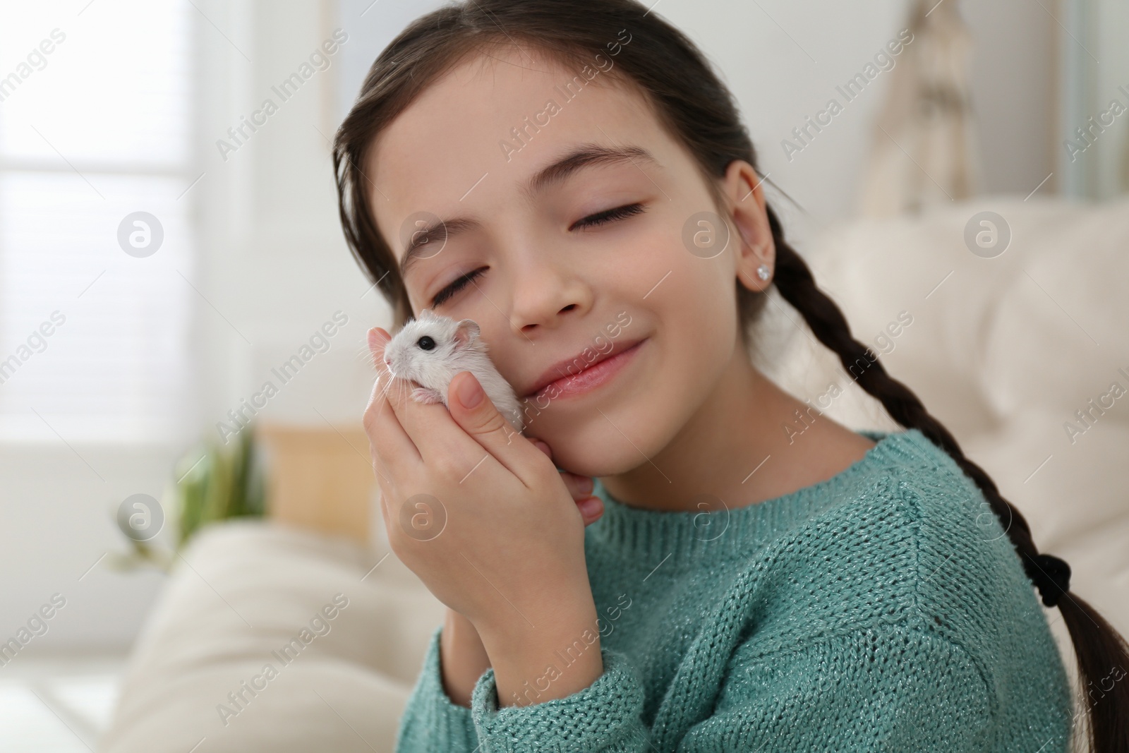 Photo of Little girl with cute hamster at home