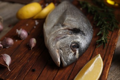 Photo of Raw dorado fish, lemon wedges and spices on table, closeup