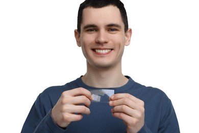 Young man with whitening strips on light background