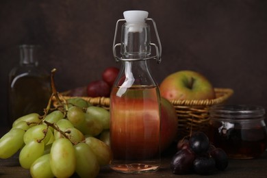 Different types of vinegar and fresh fruits on wooden table