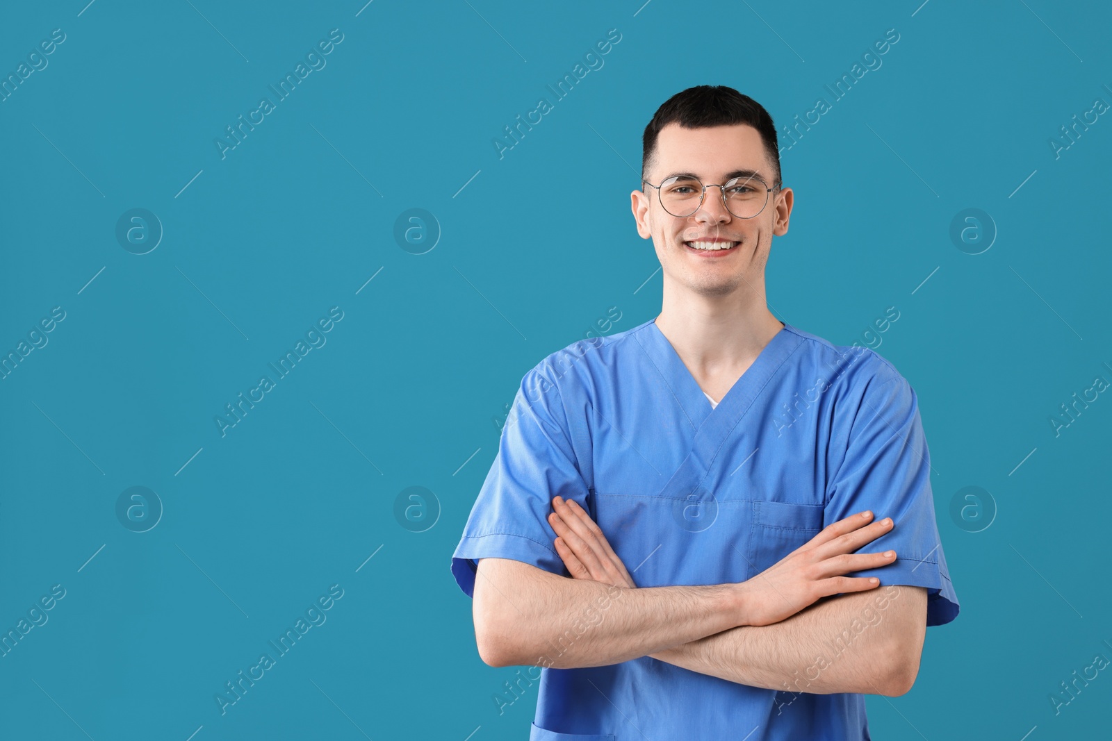 Photo of Portrait of smiling medical assistant with crossed arms on light blue background. Space for text