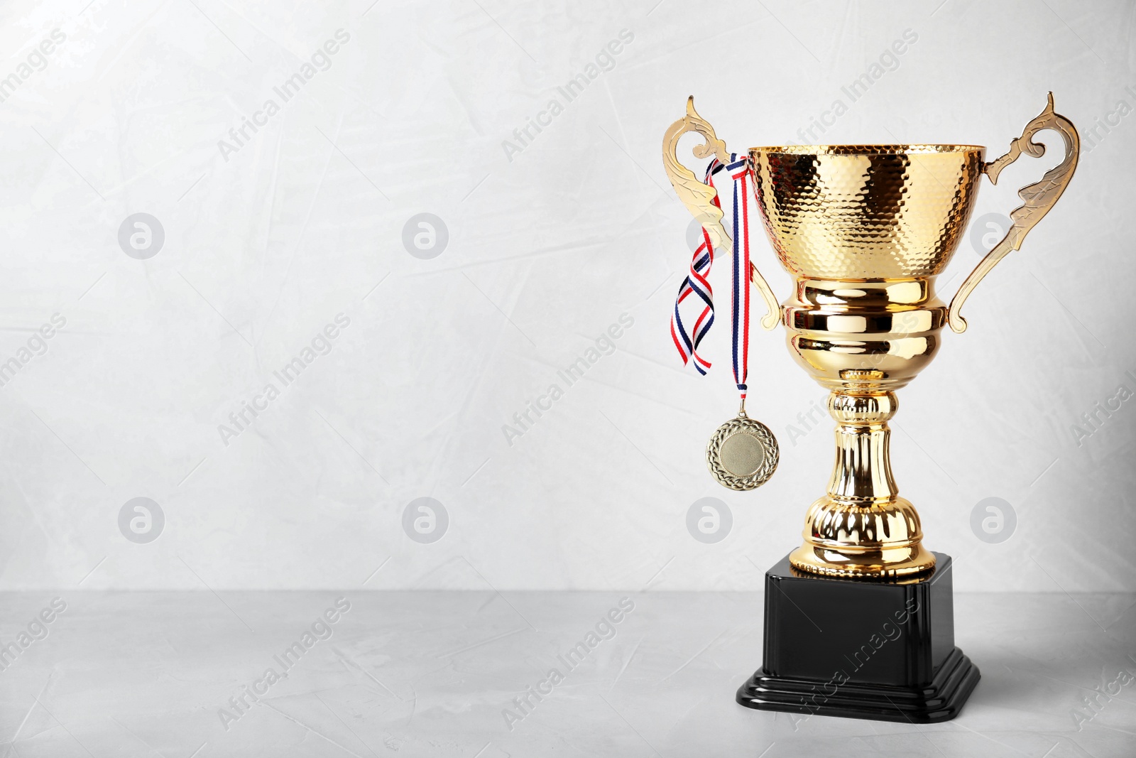 Photo of Shiny golden trophy cup and medal on white background