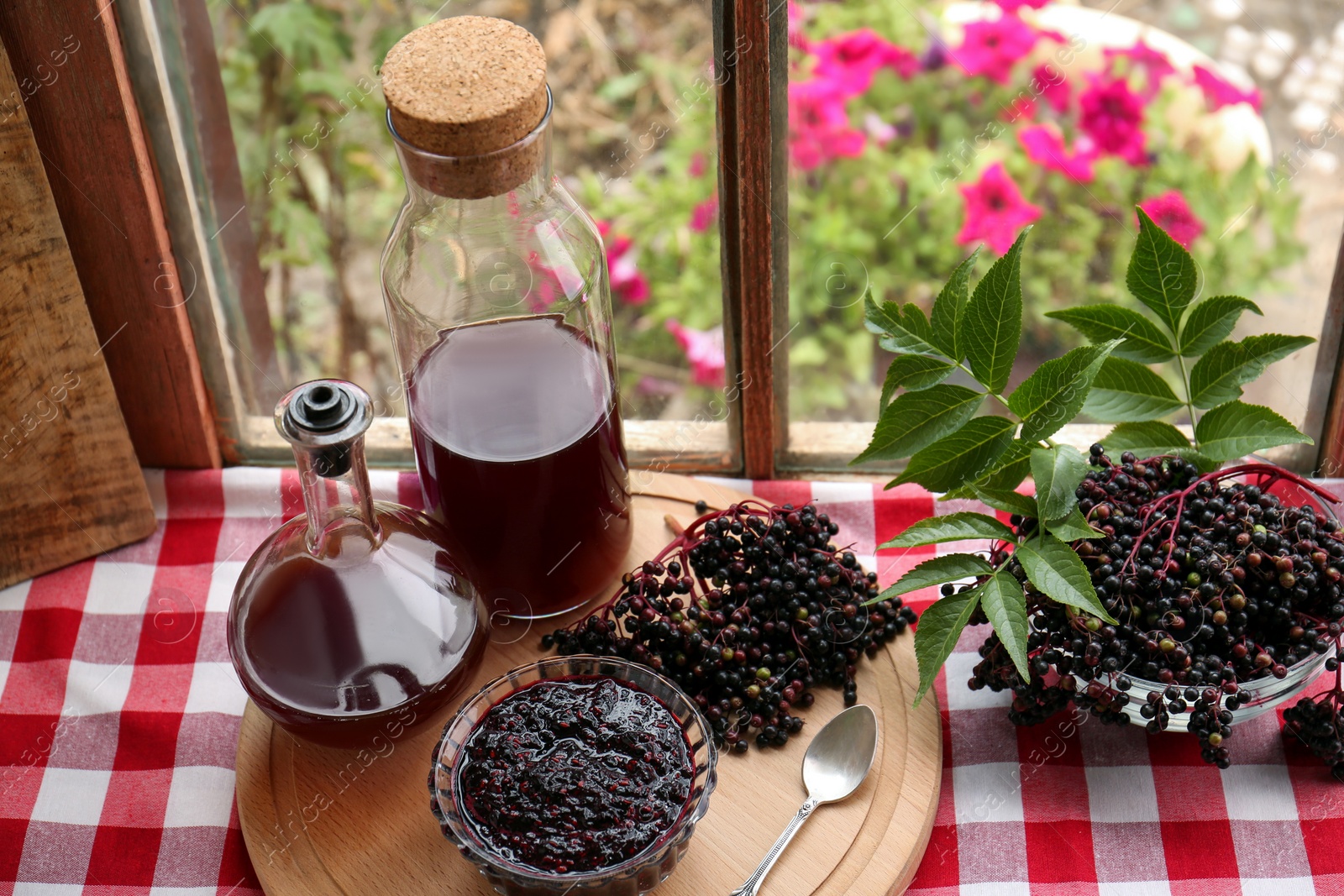 Photo of Elderberry drink and jam with Sambucus berries on table near window