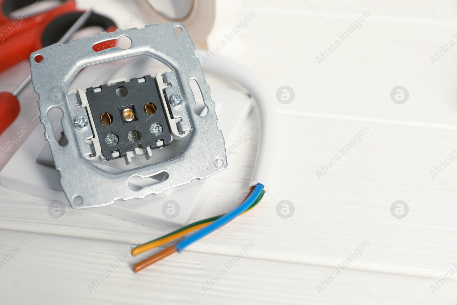 Photo of Disassembled power socket and cable on white wooden table, closeup. Space for text