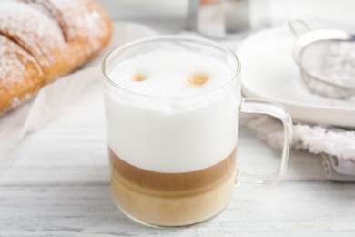 Photo of Delicious latte macchiato and croissant on white wooden table