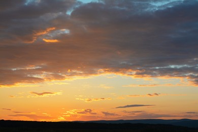 Picturesque view of beautiful countryside and cloudy sky at sunset