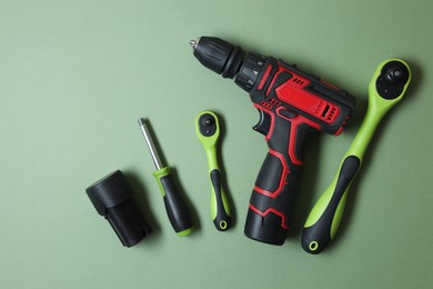 Photo of Electric screwdriver and accessories on pale green background, flat lay