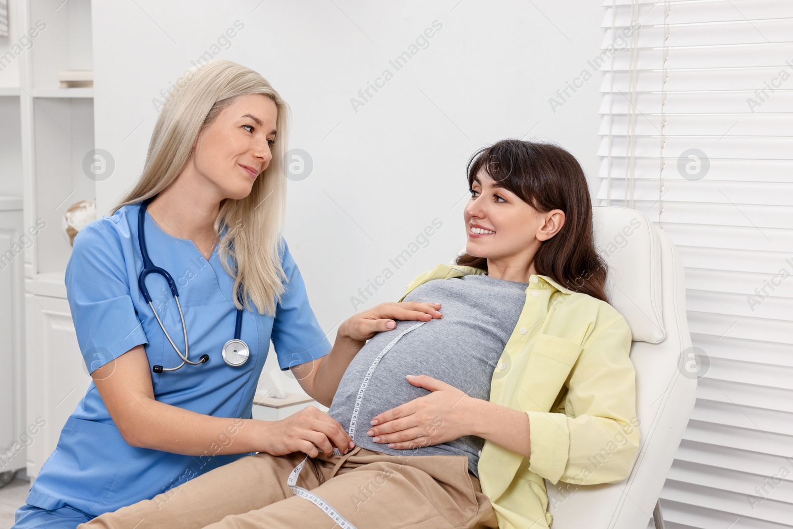 Photo of Pregnancy checkup. Doctor measuring patient's tummy in clinic