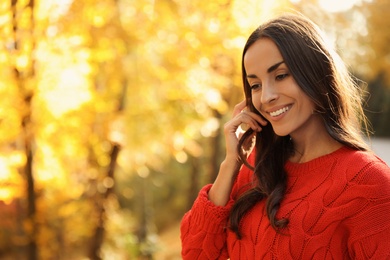 Beautiful woman wearing red sweater in sunny park. Autumn walk