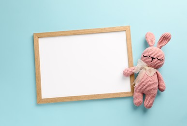 Photo of Blank white board with toy bunny on turquoise background, flat lay. Space for text