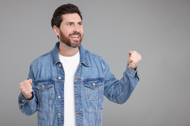 Portrait of happy surprised man on grey background, space for text