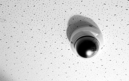 Photo of Modern CCTV security camera on white ceiling. Space for text