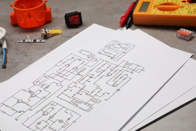 Wiring diagrams, digital multimeter and other electrician's equipment on grey table