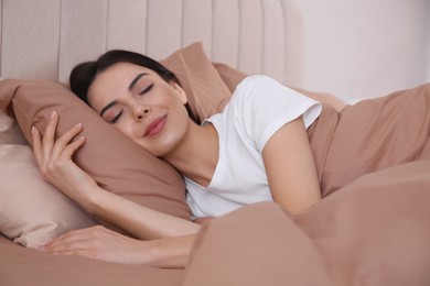 Photo of Woman sleeping in comfortable bed with beige linens