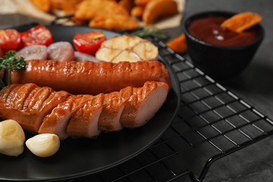 Photo of Delicious grilled sausages and vegetables on grey table, closeup