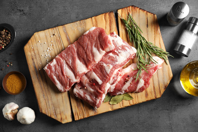 Photo of Raw ribs with herbs and spices on grey table, flat lay