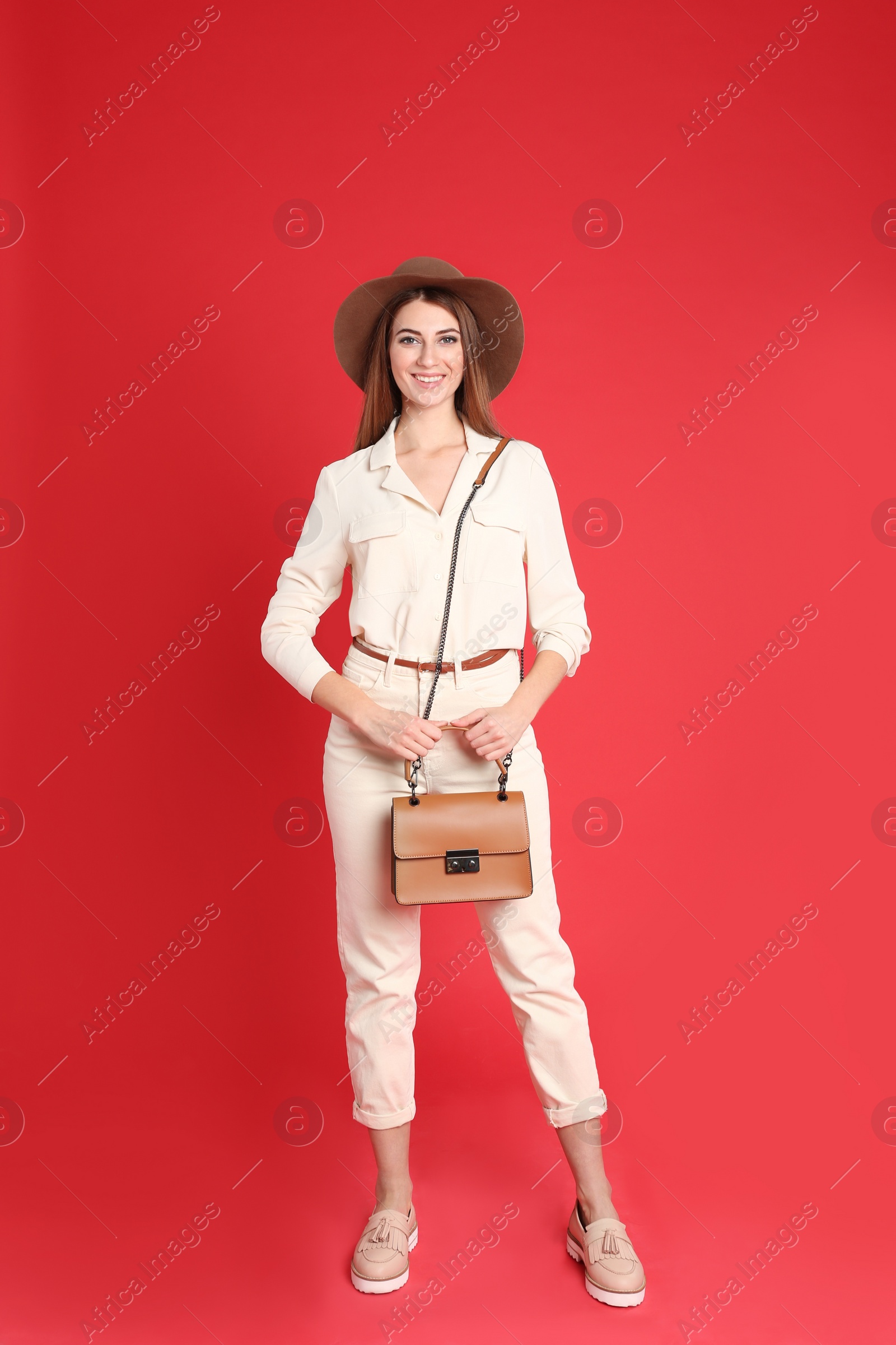 Photo of Beautiful young woman in casual outfit with stylish bag on red background