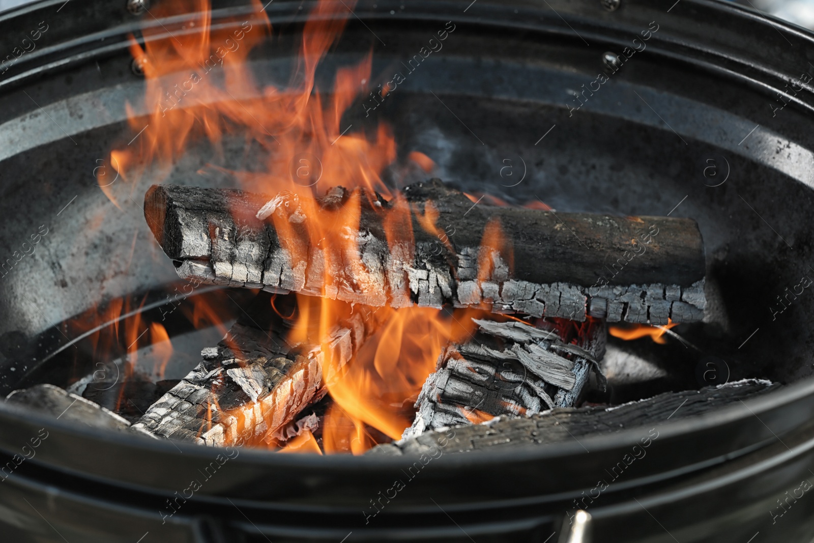 Photo of New modern barbecue grill with burning firewood, closeup